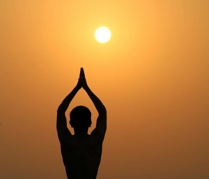 Person stretching outdoors during a golden sunset.